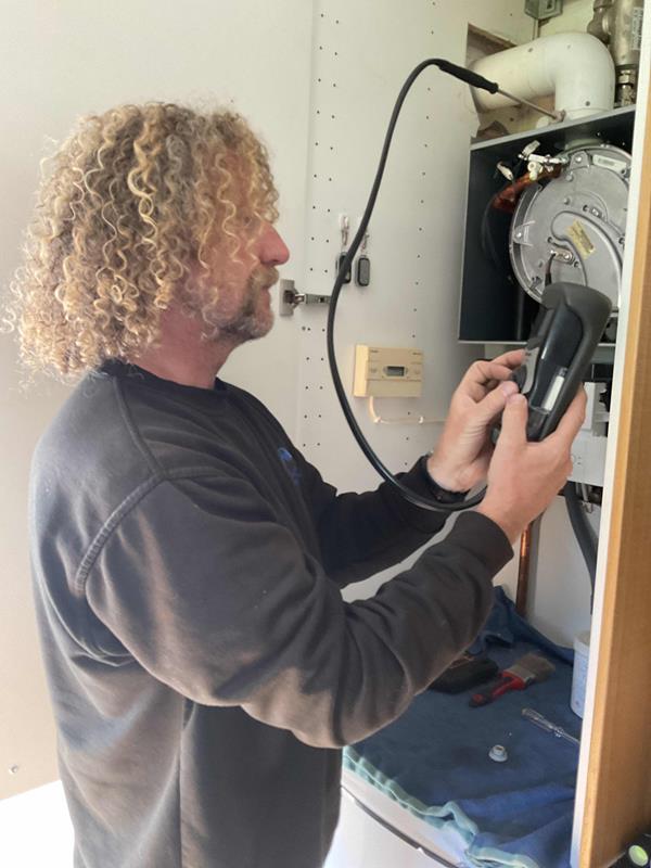 Plumber Greg servicing a boiler by checking an electronic device